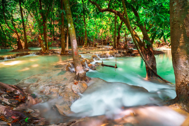 温泉温泉自然浴池被红黄树叶环绕。在秋叶中，瀑布落在许多树叶之间，在秋叶中树叶的颜色变化图片下载