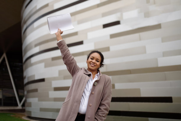 身着职业装的非裔美国女经理在城市风景的背景下为一笔交易感到高兴。本空间图片下载