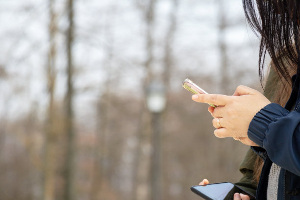 一个女人拿着手机看着她的手机。图片下载