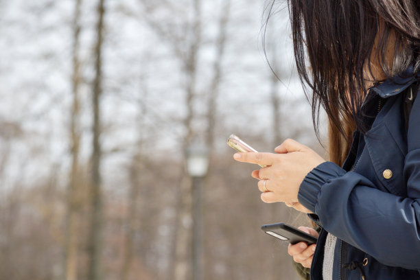 一个女人拿着手机看着她的手机。图片下载