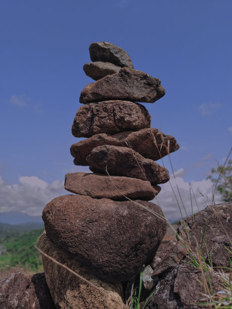 印尼南苏拉威西巴鲁马多山山顶的石堆平衡的照片，正午的背景是美丽的蓝天。平衡的概念，稳定，稳定。图片下载