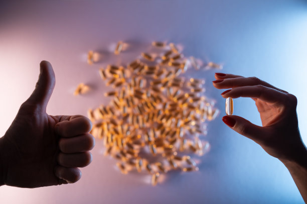 喜欢手势和手握鱼油胶囊欧米茄3在紫色的背景图片下载