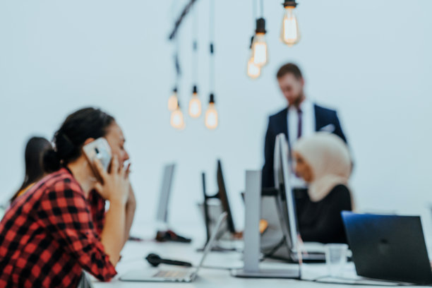 一个美女一边用笔记本电脑工作，一边看着她的智能手机的特写图片下载