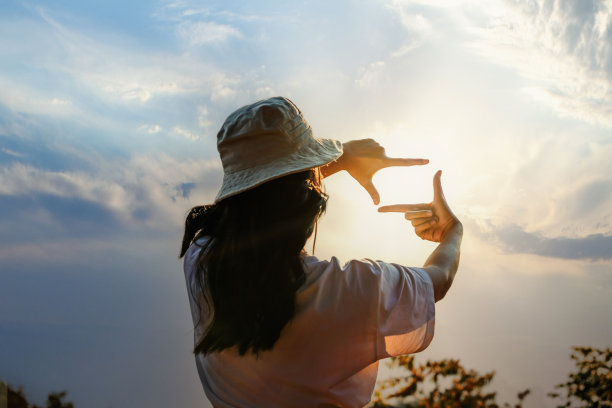 女人的手勾勒出日出时远处的景色。夕阳下，女人用手围着风景做画框，构思未来。经营理念。新年规划与愿景理念图片下载