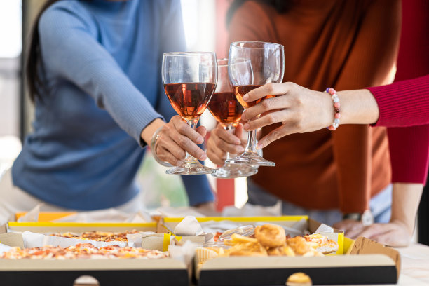 同事们在披萨派对上吃午餐，在质朴的木桌上吃着什锦披萨，喝着红酒，庆祝快餐午餐图片下载