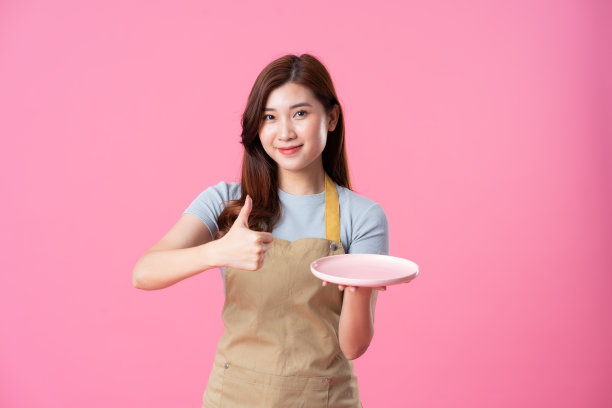 粉红色背景上穿着围裙的亚洲女孩的肖像图片下载