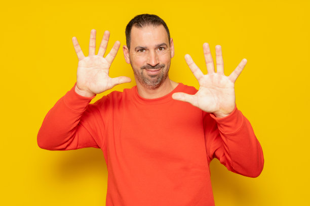 一名身穿红色套头衫、短发的白人男子的正面照片，他的手掌对着他，相机对着手掌，触摸着一个交互式虚拟屏幕图片下载