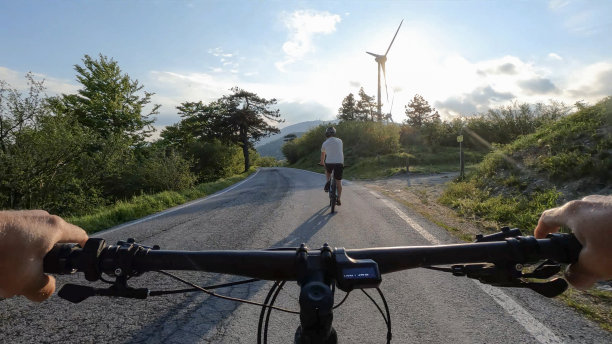 第一人称视角跟踪前面的男性摩托车手，风力涡轮机图片下载