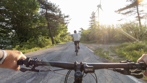 第一人称视角跟踪前面的男性摩托车手，风力涡轮机图片下载