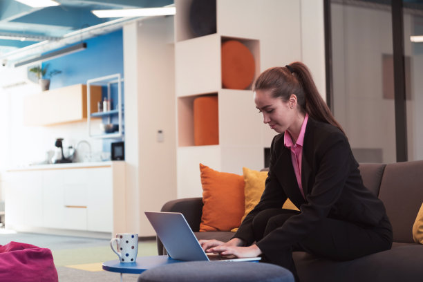 忙碌的女商人使用智能手机。快乐的年轻女商人独自在现代共享开放空间办公场所。女商人在办公室里与客户交流。图片下载