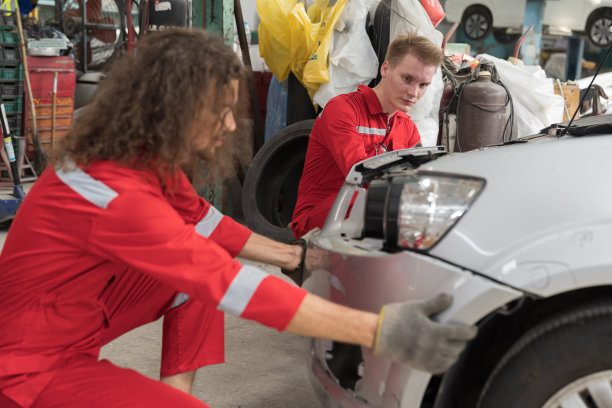 一群男汽车技工在汽车修理厂组装汽车零件。在车库车间工作和安装汽车部件的技术团队图片下载