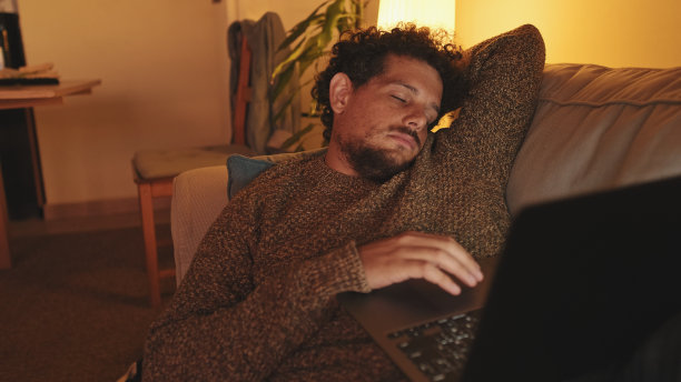 那家伙拿着笔记本电脑躺在客厅的沙发上，劳累过度，睡着了图片下载