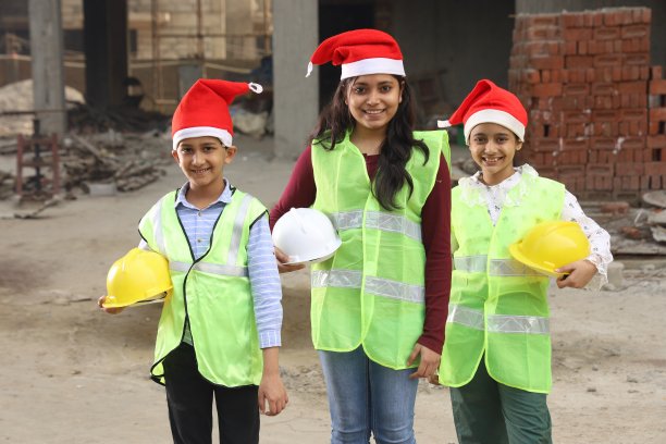 年轻的印度学校的孩子们作为榜样工程师在建筑工地工作。他们手里拿着建筑工程师的头盔。像圣诞老人一样戴着圣诞帽。图片下载