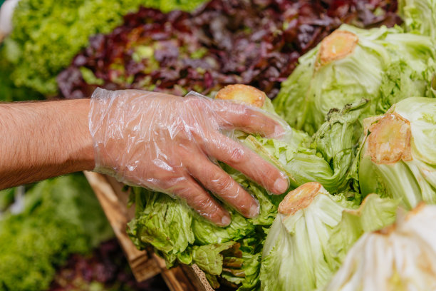 一个男人的手在商店里挑选沙拉。健康食品的概念，生物、素食、饮食。图片下载