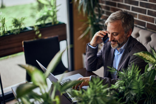 俯视图，一个微笑的餐馆老板，使用手机和笔记本电脑。图片下载