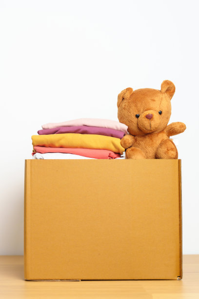儿童捐赠，慈善，志愿者，给予和交付的理念。亲手捐赠小熊娃娃和衣服到家里的纸板箱，以支持和帮助穷人，难民和无家可归的人。文本复制空间图片下载