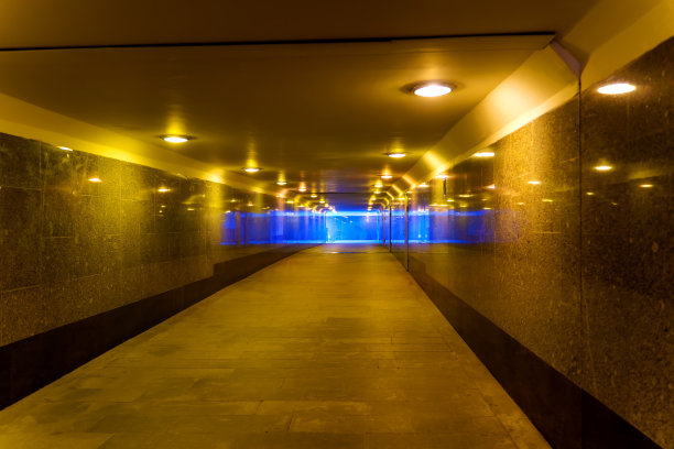 花岗岩墙壁的地下通道被黄色的灯照亮图片下载