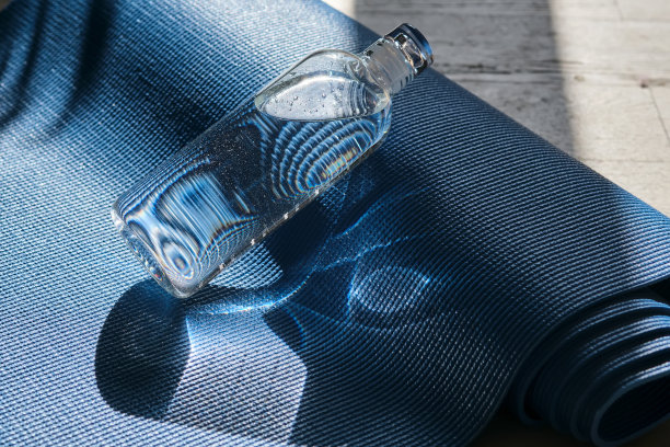 瑜伽垫上可重复使用的玻璃水瓶。图片下载