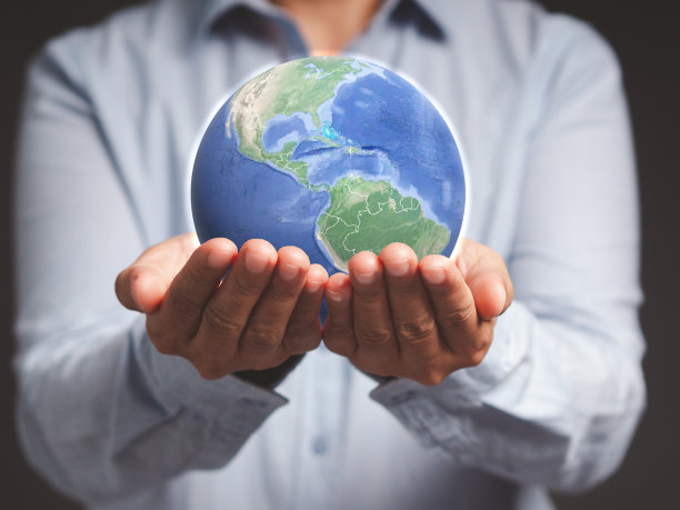 一个年轻人站在灰色的背景下，拿着大地。图片下载