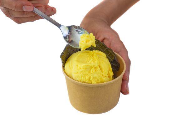 拿着勺子的手拿着一块自制的芒果冰淇淋，孤立在白色的背景上图片下载