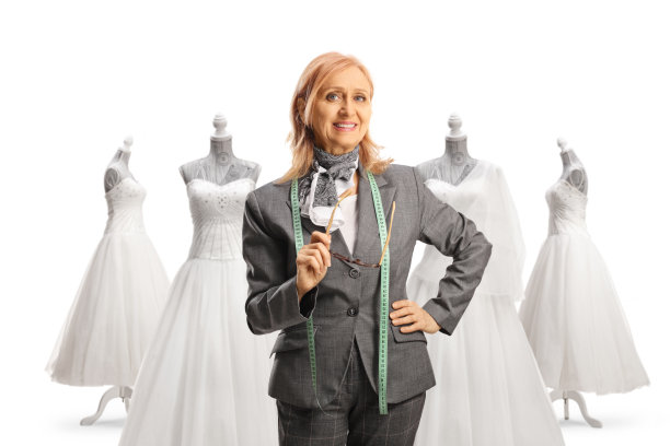 成熟的时装设计师拿着眼镜，在新娘礼服前摆姿势图片下载