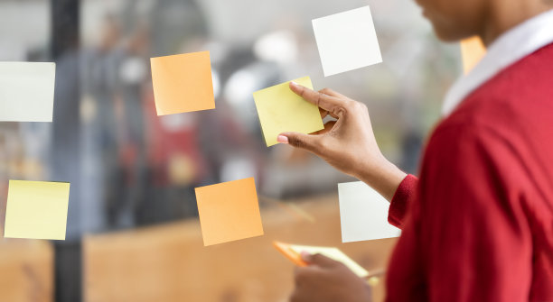 女商人的手在玻璃墙上贴便条的特写。图片下载