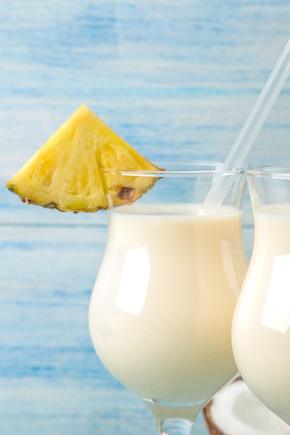 鸡尾酒冰镇朗姆酒。清凉的椰子汁和菠萝汁鸡尾酒。夏天喝。鸡尾酒的准备。在蓝色的木制背景。特写镜头图片下载