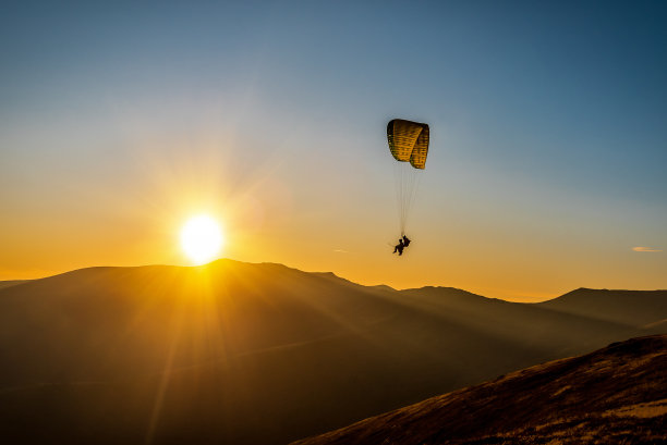 在喀尔巴阡山脉的日出中，滑翔伞的剪影图片下载