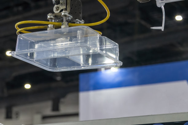 注塑机机械臂夹紧塑料容器部件。图片下载