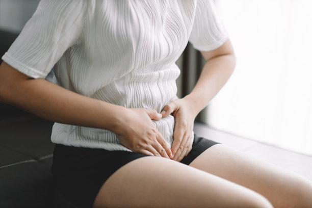 年轻亚洲女性坐在家里的床上胃痛，健康问题身体炎症，月经周期每月一天，月经概念。图片下载