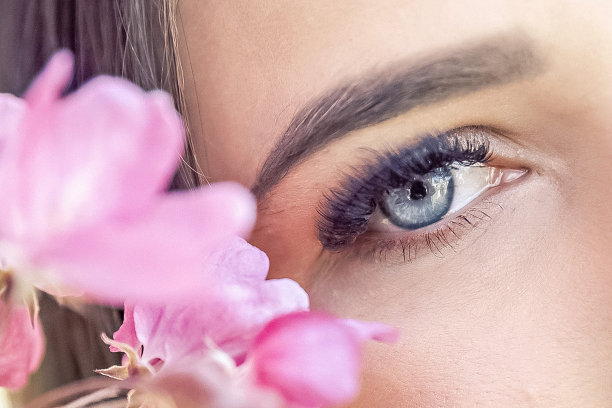 一个美丽浪漫的年轻女子的肖像，与一棵盛开的苹果树上的粉红色花朵的特写。化妆品，美容，时尚的理念。春天开花图片下载