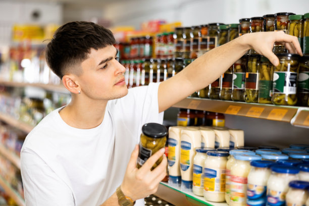 专注的年轻人在超市挑选罐头食品图片下载