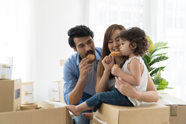 搬家、按揭、家庭、房地产概念。幸福的家庭，爸爸，妈妈和可爱的小女儿宝宝蹒跚学步的女孩在搬进新居时吃零食图片下载