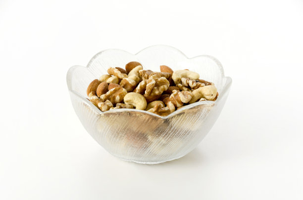 在白色背景的玻璃碗里混合坚果。图片下载