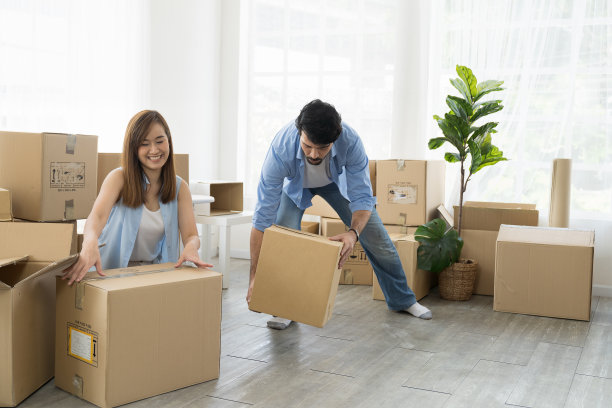 搬家、按揭、家庭、房地产概念。幸福的夫妇搬着纸板箱搬进新家。成年男人和女人收拾箱子搬新家图片下载