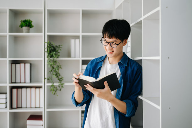 男学生在图书馆记笔记，年轻的亚洲人在大学图书馆坐在书桌前做作业图片下载