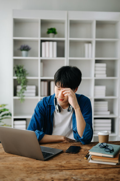 亚洲商人因为在办公室用平板电脑工作而感到压力、无聊和过度思考。图片下载