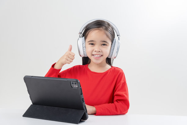 小女孩亚洲可爱戴上耳机，用笔记本电脑和老师视频通话，在电脑上在线学习，在家上学的概念图片下载