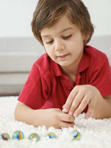 男孩躺在地毯上玩弹珠图片下载