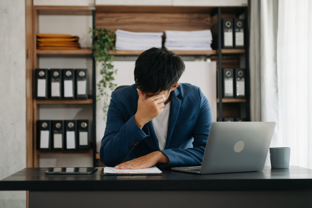 失意的年轻商人坐在办公室的办公地点用笔记本电脑工作图片下载