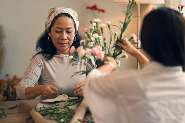 快乐的退休亚洲妇女喜欢在车间里插花。图片下载
