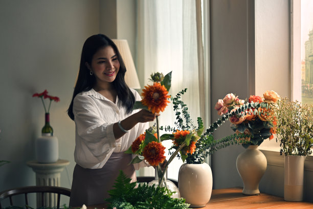 漂亮的亚洲女人在家里插花。图片下载