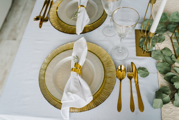节日餐桌与盘子，金色餐具和桉树叶，蜡烛。餐桌装饰为舒适的秋季节日聚会在厨房。前视图。设计元素。弹簧工作台设置图片下载