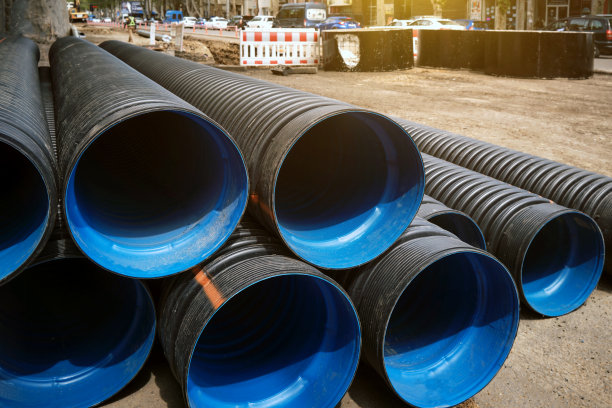 在城市的街道上堆放着大型的塑料波纹水管。图片下载