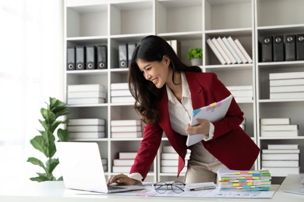 商务女性办公室工作，整理文件，未完成的文件堆和使用笔记本电脑。财务会计概念图片下载