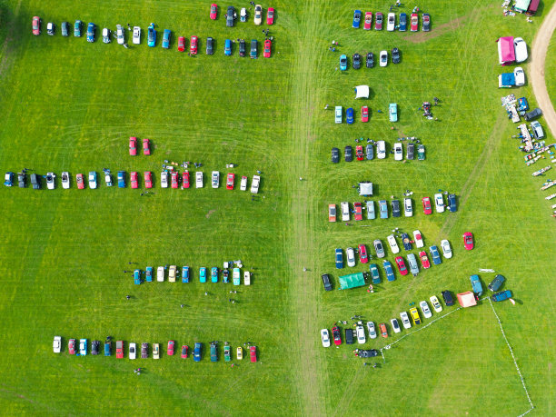 无人机俯瞰远处停在草地上的经典汽车。图片下载