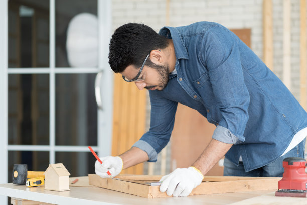 专业男木匠在木工车间用量具、金属方尺、比尺、直尺等工具标出木材的细节。中小企业，创业和小型企业的概念图片下载