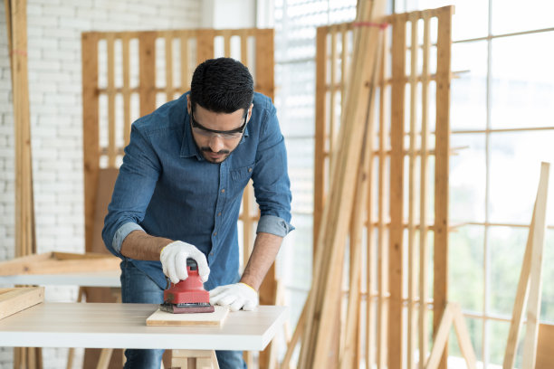 专业男木匠在木工车间使用电子打磨工具。亚洲男性细木工工作主要从事木材的制作和木制家具的翻新。中小企业，创业和小型企业的概念图片下载