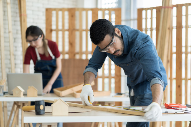 专业男木匠在木工车间使用卷尺测量木材。亚洲男性细木工和木制家具的翻新。中小企业，创业和小型企业的概念图片下载