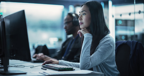 年轻漂亮的亚洲女专家与专业的同事一起在电脑上工作。数据保护中心，服务器设施，存储硬件和企业科学氛围图片下载